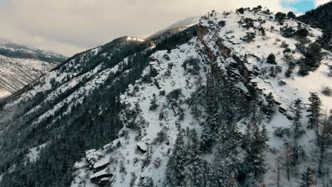 Aerial-shot-of-a-snowy-mountain-ridge-line-and-forest-in-Utah-in-winter