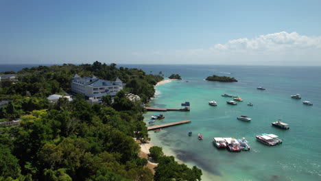 Aerial-flying-backwards-on-a-Caribbean-island-with-a-dock-and-boats,-Cayo-Levantado,-Dominican-Republic