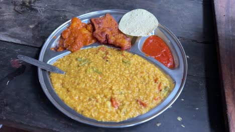 Khichuri-with-alu-dum,-chutney-and-papad-served-on-a-plate-by-a-Bengali-restaurant