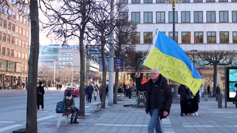 Un-Hombre-Camina-Con-Una-Bandera-Ucraniana-Con-Putin-Fuera-De-Ucrania,-Suecia