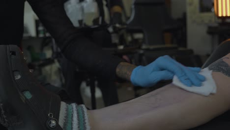 a-woman-in-a-tattoo-shop-sterilizes-the-leg-of-a-client-in-preparation-of-inking-a-tattoo-onto-her-skin