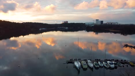 Forward-aerial-of-sailboats-at-marina-by-shore-in-Stockholm-at-sunset
