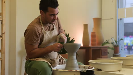 Male-craftsman-slow-motion-forming-clay-vase-sculpture-on-workshop-pottery-wheel