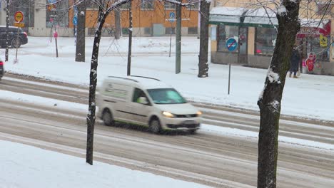 Trucks,-snow-plow-and-cars-drive-on-snowy-street-in-Stockholm,-Sweden