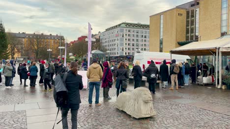 People-wait-for-covid-vaccine-by-mobile-station-in-rainy-Sweden