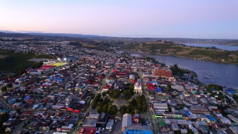 Aerial-establishing-shot-of-Castro-Sprawling-cityscape,-Orbiting-view,-Chiloé-Island