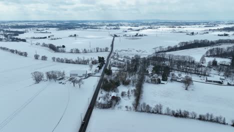 Driving-cars-on-rural-road-between-snow-covered-agricultural-fields-in-Pennsylvania