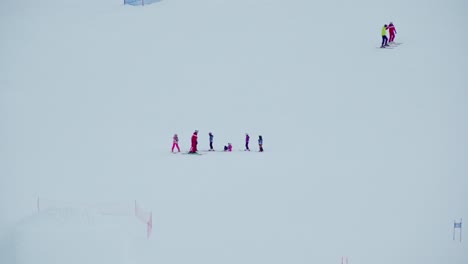 Ski-instructor-helping-up-kids-during-a-lesson-on-a-ski-slope-for-beginners