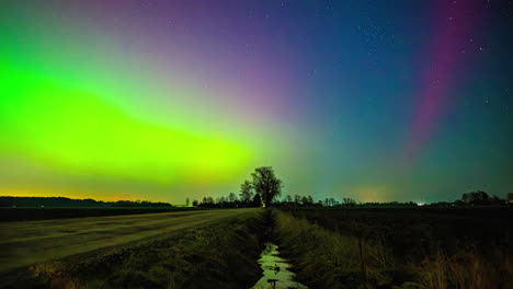 Timelapse-of-the-vibrant-Northern-lights-glowing-above-a-ditch-and-rural-fields