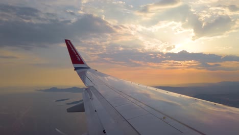 POV-of-wing-of-Norwegian-airplane-approaching-coastline-at-sunset