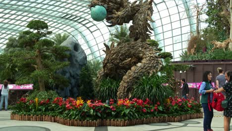 Wooden-dragon-sculpture,-the-centrepiece-of-Flower-Dome-glass-greenhouse-conservatory-at-Gardens-by-the-bay-during-festive-season,-to-celebrate-Lunar-new-year,-tilt-up-shot-of-the-dragon