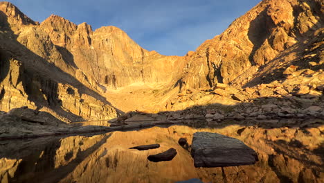 Chasm-Lake-sunrise-on-Longs-Peak-fourteener-Rocky-Mountain-National-Park-RMNP-first-light-summer-hike-mountaineer-adventure-trail-reflection-calm-water-stunning-scenic-landscape-slow-pan-left-motion