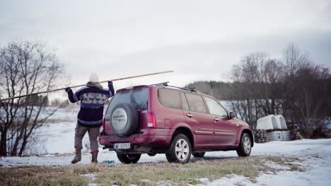 The-Man-is-Placing-a-Plank-of-Wood-Onto-the-Roof-of-His-Car-in-Indre-Fosen,-Trondelag-County,-Norway---Static-Shot