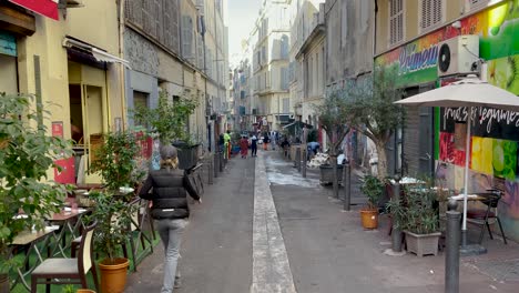 People-walk-on-narrow-colorful-pedestrian-street-in-Marseille,-France