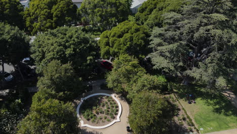 Aerial-View-of-Beverly-Hills-Sign,-Gardens-Park-and-People-on-Sunny-Day,-Aerial-Drone-Shot