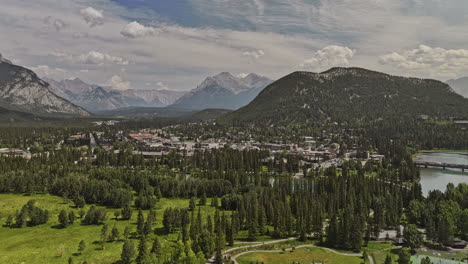 Banff-AB-Canada-Aerial-v37-drone-flyover-Bow-river-capturing-pristine-turquoise-water,-picturesque-townscape-surrounded-by-forested-valleys-and-mountain-ranges---Shot-with-Mavic-3-Pro-Cine---July-2023