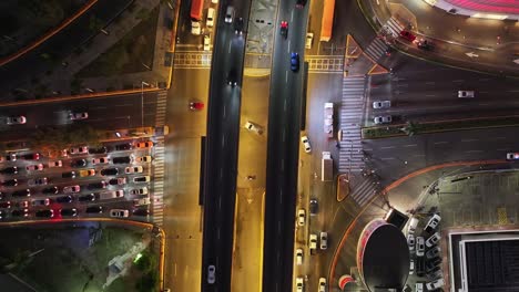 Vista-De-Arriba-Hacia-Abajo-De-Automóviles-Que-Cruzan-Intersecciones-Por-La-Noche-En-Santo-Domingo,-República-Dominicana