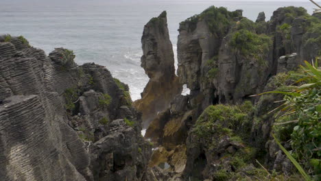 Slow-motion-waves-crash-around-a-sea-column-and-cliffs---Punakaiki,-New-Zealand