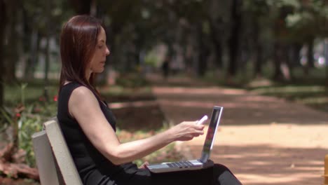 Una-Joven-Abre-Su-Computadora,-Portátil-Trabajando-En-El-Parque-De-La-Ciudad.