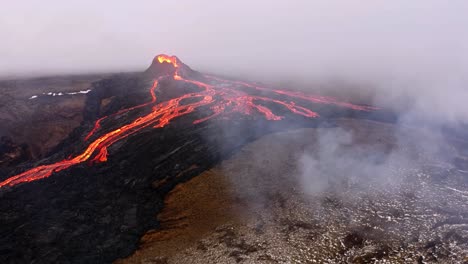 Eine-4K-Drohne-Macht-Filmische-Luftaufnahmen-Eines-Vulkans,-Der-Lava-Ausspuckt,-Inmitten-Einer-Rauchigen-Umgebung-In-Island-Und-Bietet-Einzigartige-Perspektiven-Des-Naturschauspiels