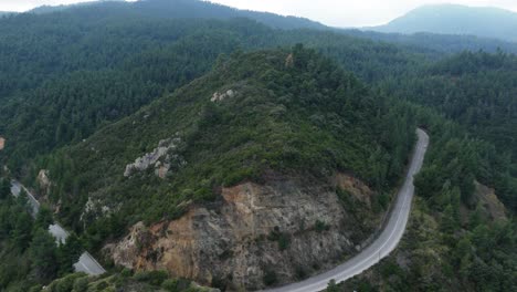 Retrocediendo-Lentamente-Revelando-Una-Colina-Verde-De-Una-Montaña-Con-Una-Carretera-En-Sithonia,-Chalkidiki,-Grecia