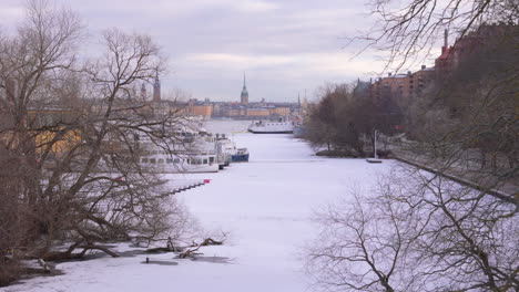 Frozen-Palsundet-with-moored-boats,-Gamla-Stan-skyline-in-distance