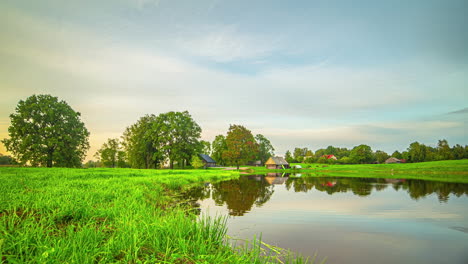 Timelapse-Scenic-Landscape-with-Lake-Reflections,-Low-Angle-Shot-with-Grass-and-Trees-on-the-Horizon