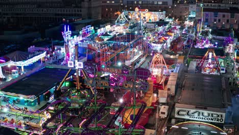 Luna-Park-En-El-Paseo-Marítimo-De-Génova-Iluminado-Con-Luces-De-Colores-Por-La-Noche,-Aéreo