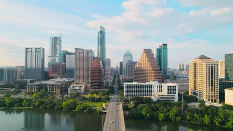 Aerial-drone-shot-of-Austin-Texas'-Congress-Avenue-bridge-overlooking-the-Texas-State-Capitol-and-downtown-Austin-city-skyline-on-the-Colorado-River-at-sunset,-with-cars,-bikers,-and-pedestrians