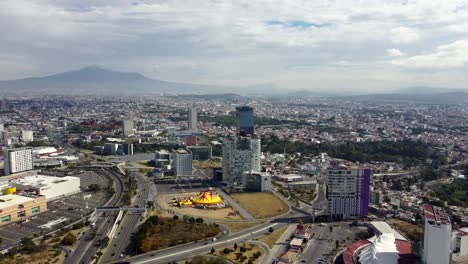 Aerial-approaching-shot-Puebla-City-with-highway,-tower-and-suburbs