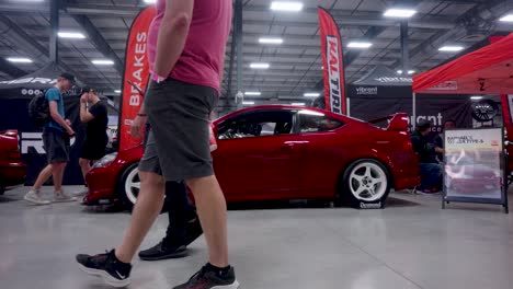 Time-lapse-People-Waling-by-Driven-Automotive-Show-Honda-Acura-Red-Race-Car-with-White-Wheels-Indoors