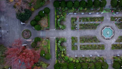 Un-Parque-Simétrico-Con-Una-Fuente-Central-Y-Autos-Estacionados,-Filmado-Durante-El-Día,-Vista-Aérea