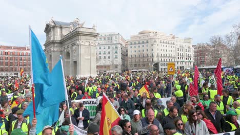 Schwenkaufnahme-Von-Spanischen-Landwirten-Und-Landwirtschaftsgewerkschaften,-Die-Die-Straßen-Blockieren,-Als-Sie-Sich-An-Der-Puerta-De-Alcalá-In-Madrid-Versammeln,-Um-Gegen-Unlauteren-Wettbewerb,-Landwirtschaft-Und-Regierungspolitik-Zu-Protestieren