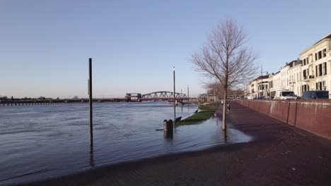 River-IJssel-invading-pavement-outside-embankment-on-sunny-day-with-clear-blue-sky