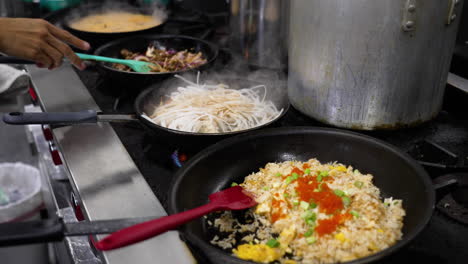 Toma-Cinematográfica-De-Una-Sartén-Tras-Otra-Llenando-La-Cocina-De-Un-Restaurante-Profesional,-El-Chef-Saltea-Verduras-En-Una-Sartén-Junto-Con-Una-Variedad-De-Otros-Platos-Hirviendo,-Control-Deslizante-En-Cámara-Lenta-4k