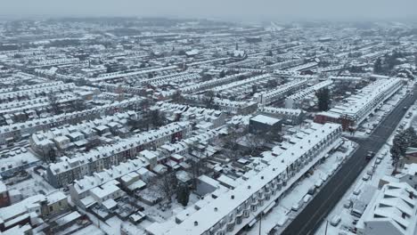 Cinematic-drone-flight-over-snowy-american-housing-area-with-homes-and-buildings-in-winter-snow