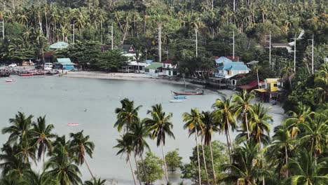 Imágenes-De-Drones,-Volando-Sobre-Palmeras-Y-Una-Bahía-Con-Casas-Y-Cabañas.