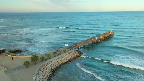 Luftaufnahme-Von-Einem-Hölzernen-Pier-In-Protaras,-Zypern,-Mit-Welligem-Meer