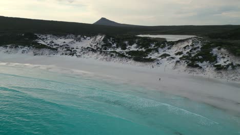 Vista-Aérea-Sobre-Thistle-Cove-En-Cabo-Legrand-Con-Alguien-Caminando-Por-El-Bach-Y-El-Pico-Francés-Al-Fondo,-Parque-Nacional-Cabo-Legrand-Cerca-De-Esperance,-Australia-Occidental