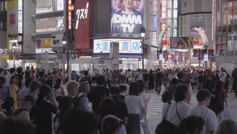 Slow-motion-shot-of-large-crowds-walking-through-the-busy-Shibuya-Crossing-at-night-Tokyo,-Japan-1