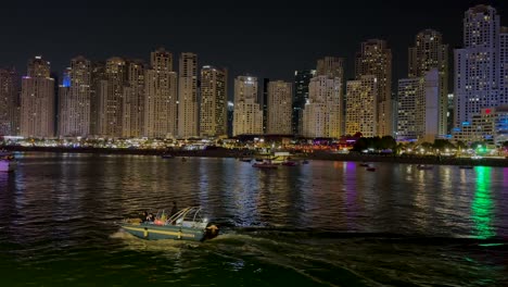 Kleine-Yacht,-Die-Abends-Auf-Der-Blue-Water-Island-Segelt,-Und-Im-Hintergrund-Die-Wolkenkratzer-Des-JBR-Dubai