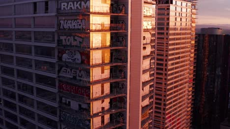 Close-up-rising-aerial-shot-of-the-extensive-graffiti-murals-on-the-Oceanwide-Plaza-towers-in-downtown-Los-Angeles,-California-at-sunset