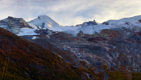 Sonnenuntergang-Goldene-Stunde-Schweizer-Alpen-Saas-Fee-Saastal-Plattjen-Zermatt-Gletscher-Schweiz-Sommer-Herbst-Herbstlicht-Auf-Berggipfeln-Gelbe-Lerche-Bäume-Bewölkt-Atemberaubende-Filmische-Langsame-Schwenkung-Nach-Links