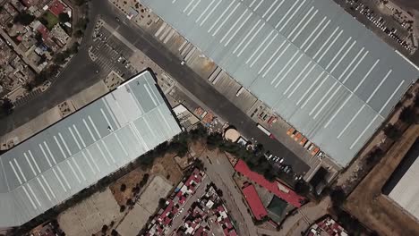 Aerial-drone-shot-over-the-edge-of-a-neighborhood-and-industrial-warehouse-area-in-Cuautitlan-Izcalli,-Mexico