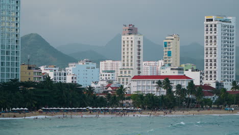 Panoramic-View-of-Nha-Trang-City-and-Hon-Chong-Beach,-Hotels-and-Resorts-Buildings-Against-Towering-Mountains-at-Sunset,-Vietnam