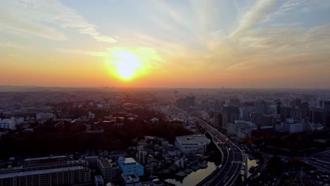 Amanecer-Sobre-El-Horizonte-De-La-Ciudad-Con-Rayos-Asomando-Por-Encima-De-Los-Edificios,-Temprano-En-La-Mañana,-Vista-Aérea