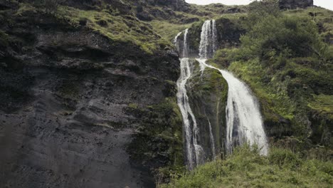 Wunderschöne-Ströme-Kleiner-Wasserfälle-Fließen-über-Eine-Mit-Grashalmen-übersäte-Felswand