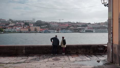 Romantisches-Paar,-Das-Sich-Unterhält-Und-Auf-Die-Uferpromenade-Von-Porto-Entlang-Des-Flusses-Douro-Zeigt-Und-Gemeinsam-Malerische-Orte-Der-Stadt-Erkundet