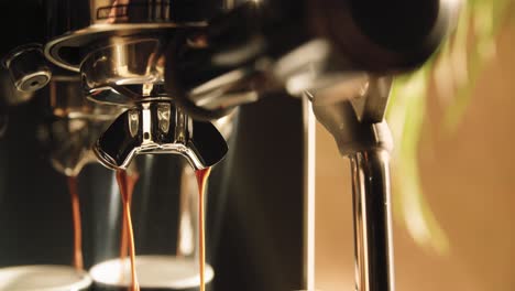Close-up-slow-motion-shot-of-creamy-hot-coffee-streaming-down-from-portafilter-valve