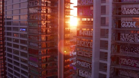 Rising-close-up-aerial-shot-with-lens-flare-of-the-colorful-graffiti-murals-on-the-unfinished-Oceanwide-Plaza-towers-at-sunset-in-downtown-Los-Angeles,-California